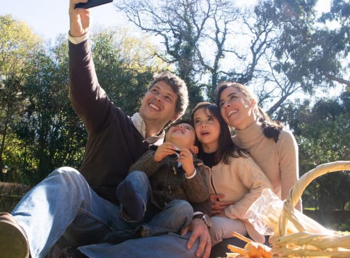 Happy family taking a selfie during a sunny picnic in a park.