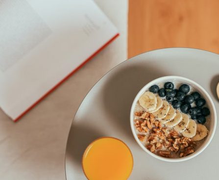 Top view of healthy breakfast with oatmeal, fresh fruit, and orange juice on a tray.