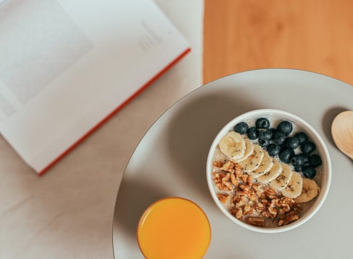 Top view of healthy breakfast with oatmeal, fresh fruit, and orange juice on a tray.